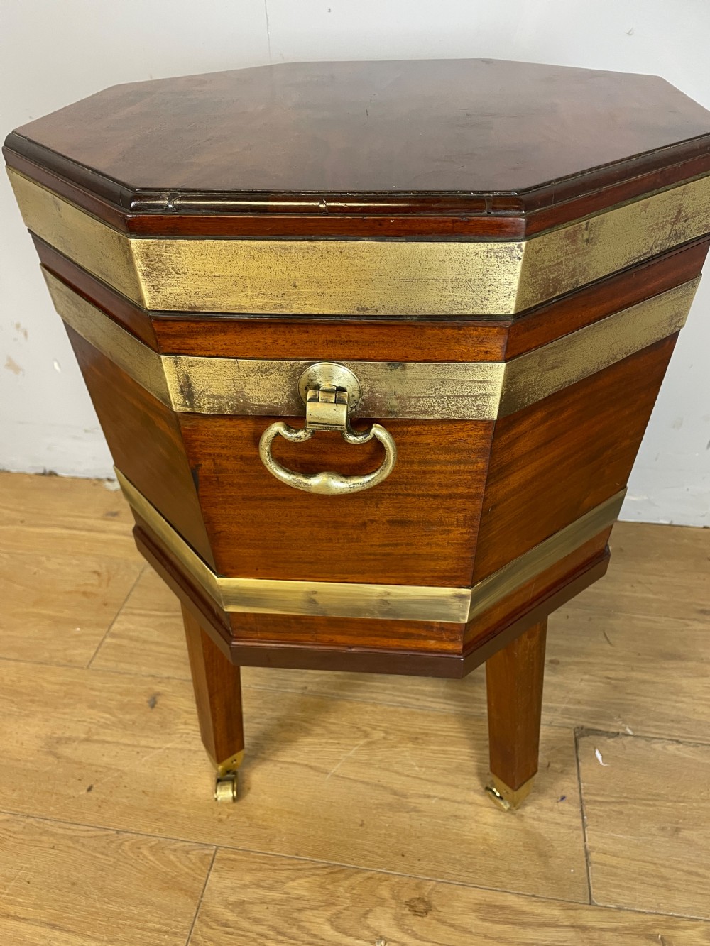 An octagonal Georgian mahogany cellarette bound with brass bands and supported by four square tapered legs on brass castors. View VIII