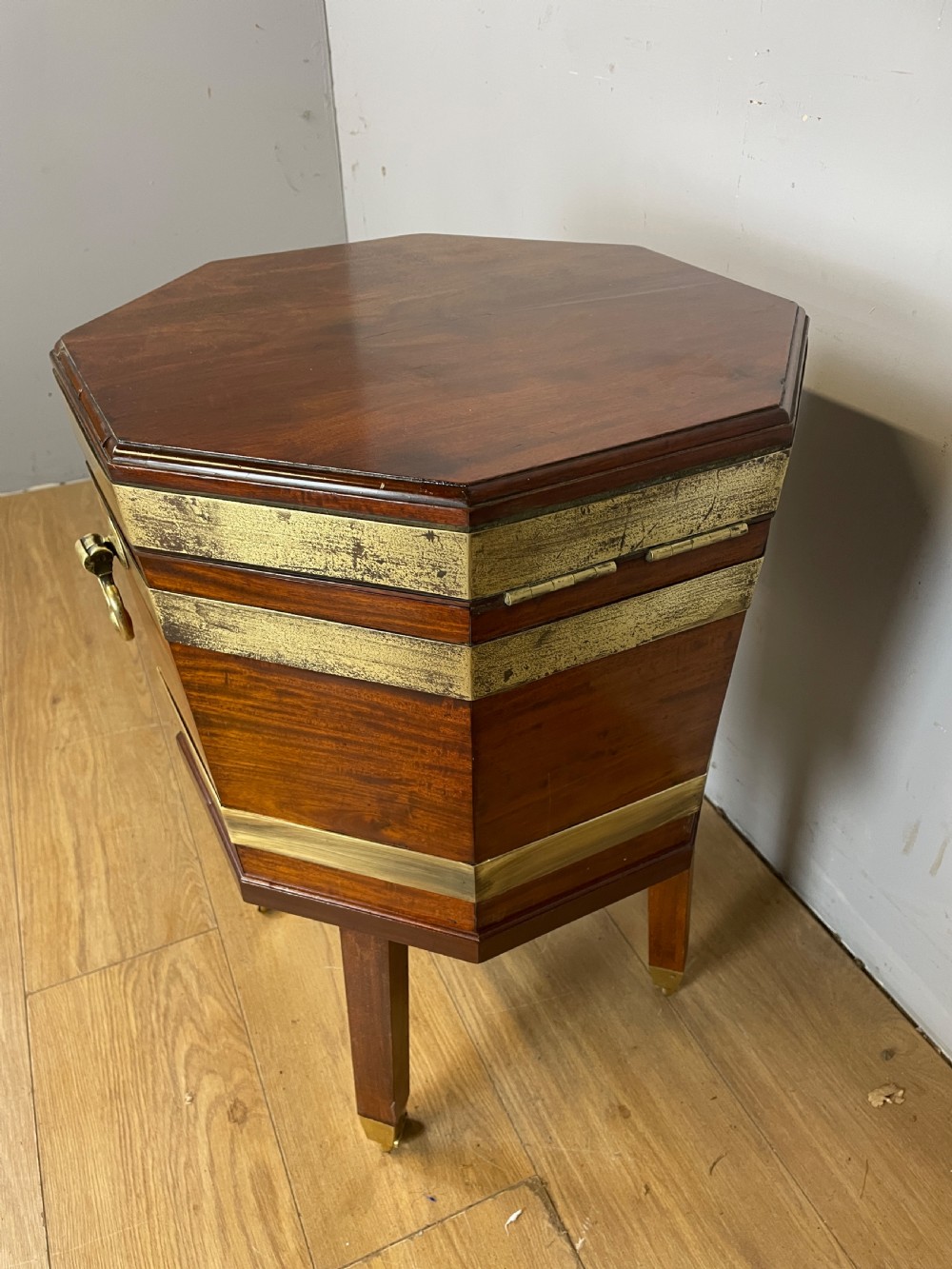 An octagonal Georgian mahogany cellarette bound with brass bands and supported by four square tapered legs on brass castors. View IX