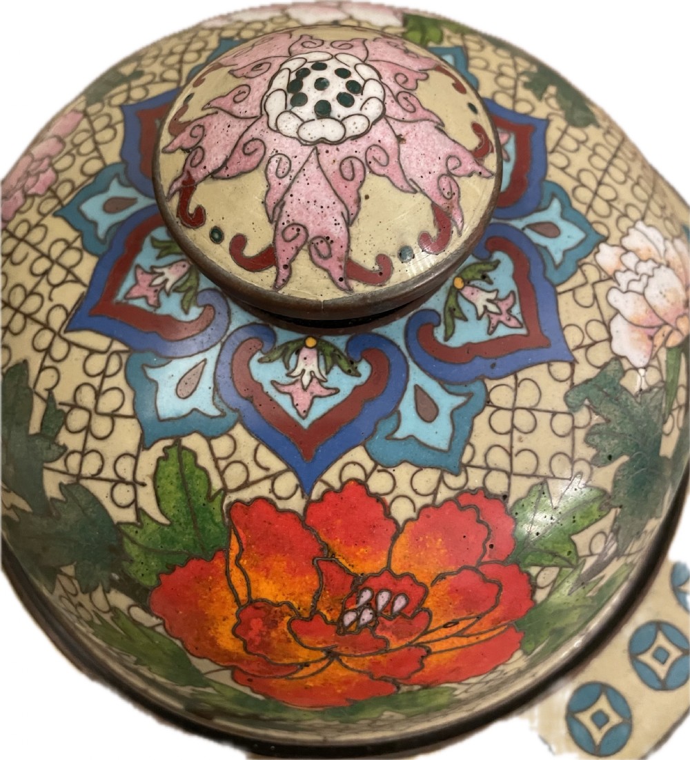 An antique cloisonne covered vase with a cream patterned background decorated with pink and red peony blossoms, green leaves, and a domed lid. View VII