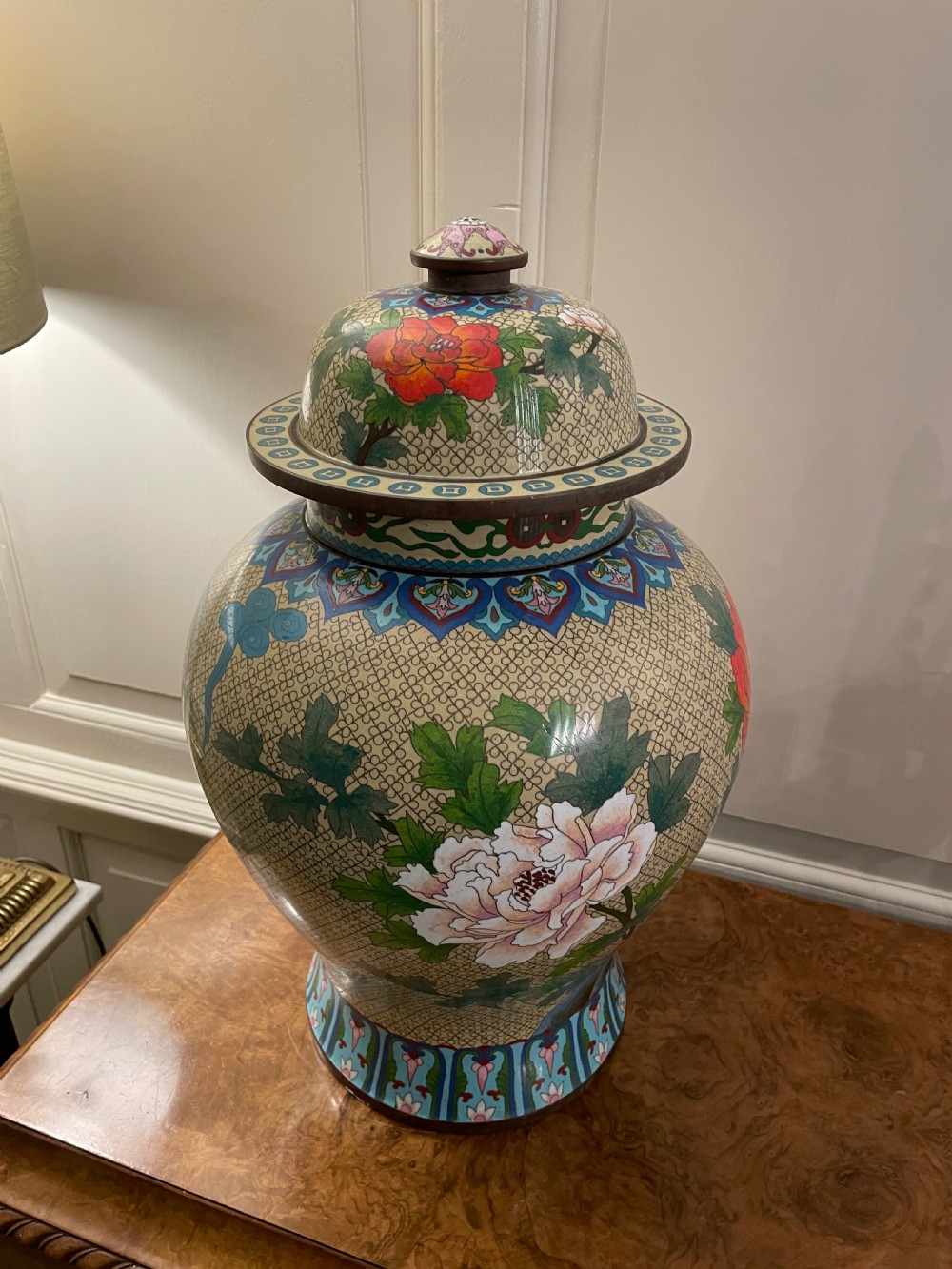 An antique cloisonne covered vase with a cream patterned background decorated with pink and red peony blossoms, green leaves, and a domed lid. View XIII
