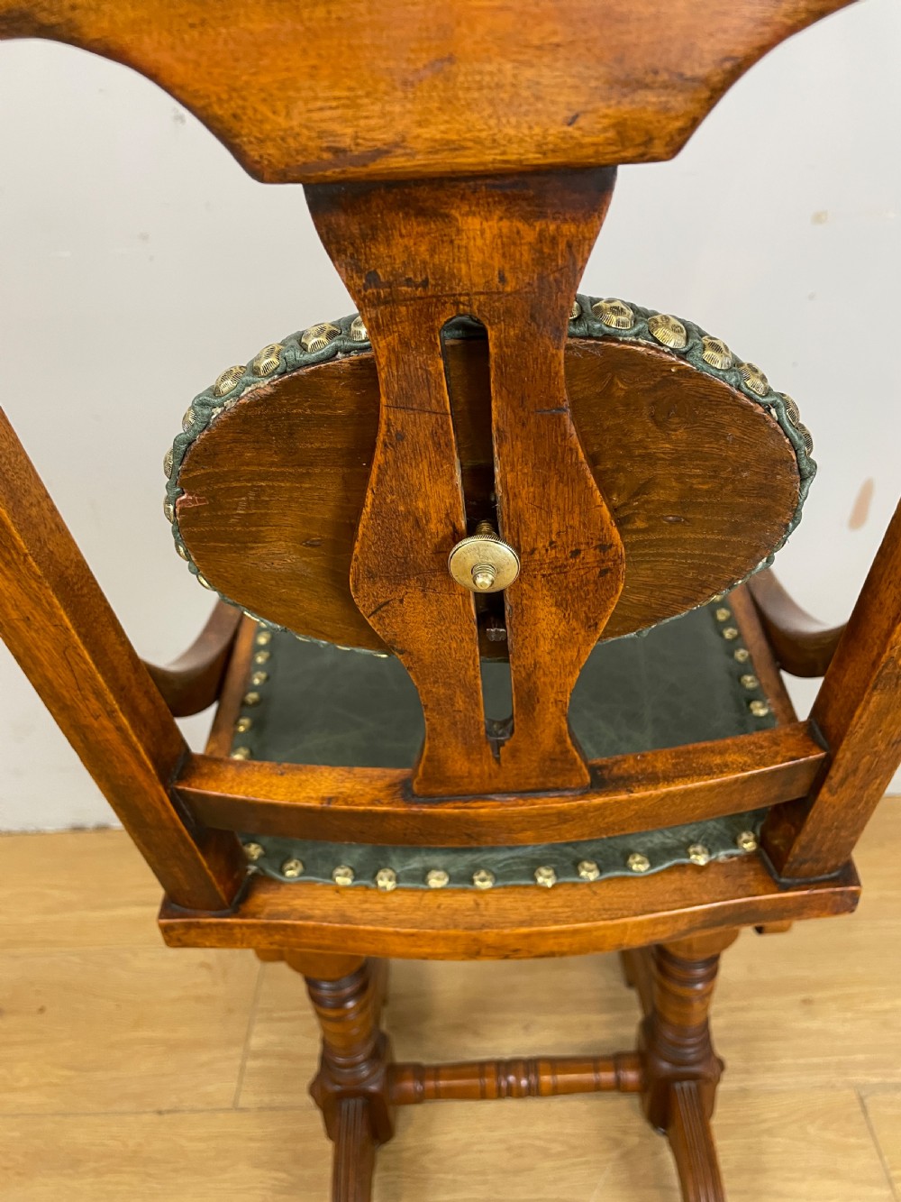 A late nineteenth-century Victorian patent music chair in polished oak featuring a green leather seat and lumbar pad trimmed with brass studs. View VIII