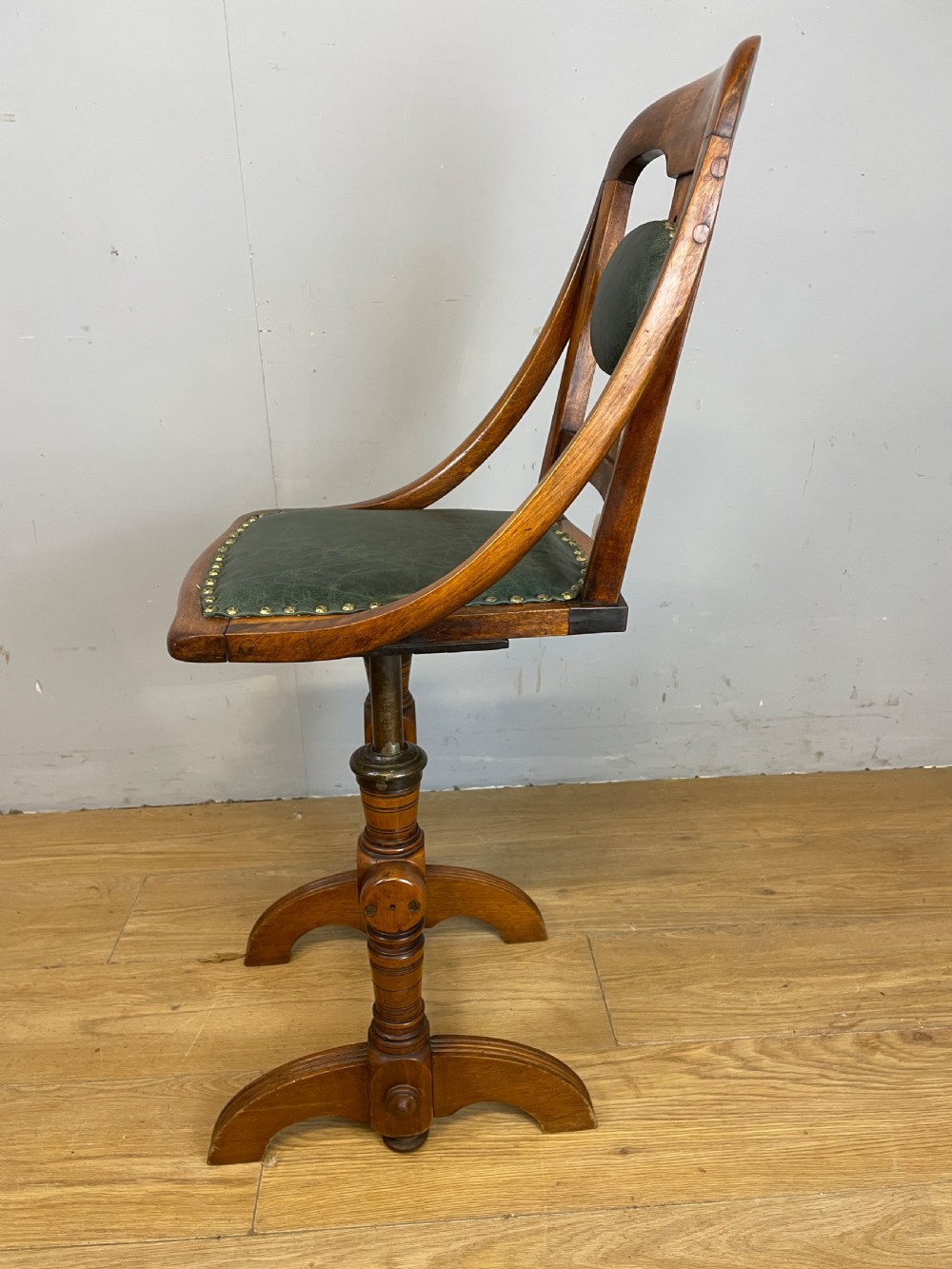 A late nineteenth-century Victorian patent music chair in polished oak featuring a green leather seat and lumbar pad trimmed with brass studs. View IX