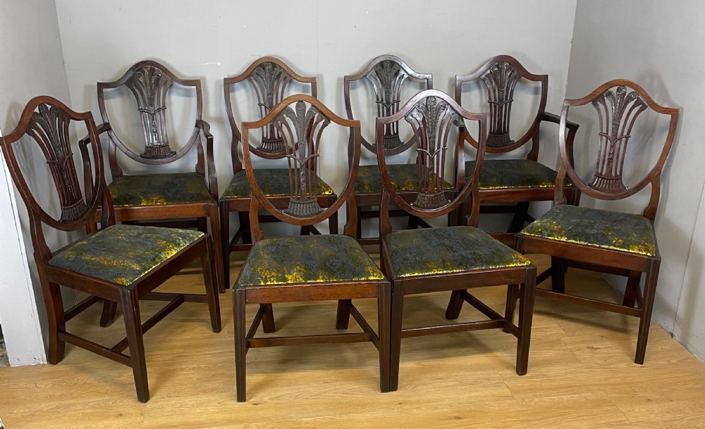 Set of eight Georgian mahogany shield back dining chairs including two armchairs with carved splats and patterned upholstered seats.