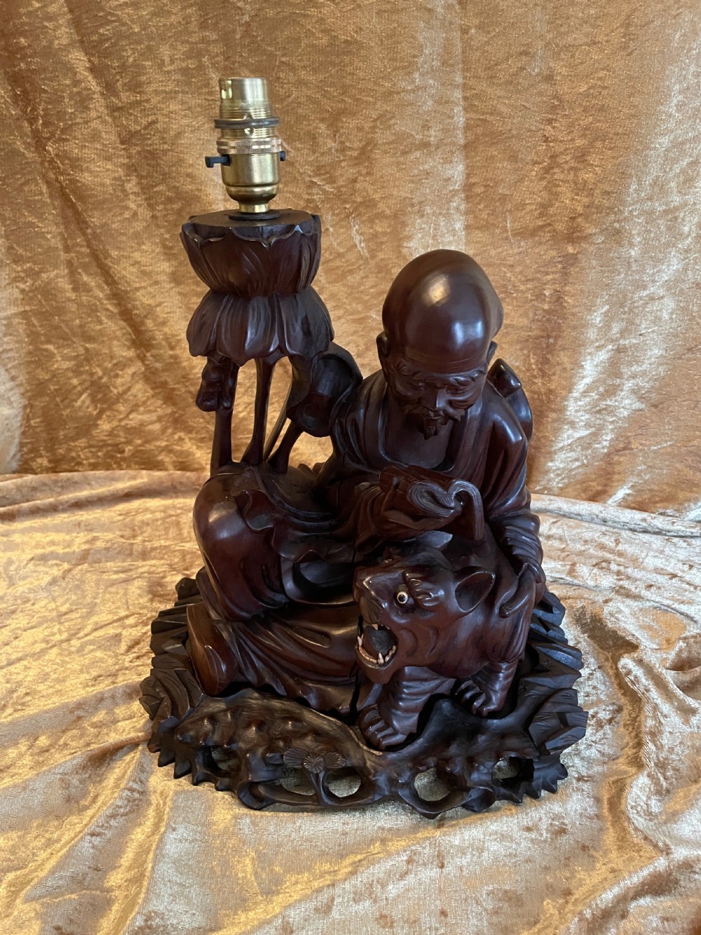 Late nineteenth-century Chinese carved dark wood table lamp depicting a seated scholar figure reading beside a tiger on a carved base with brass bulb holder. View II
