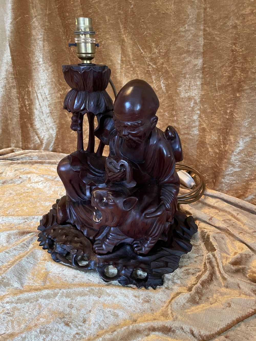 Late nineteenth-century Chinese carved dark wood table lamp depicting a seated scholar figure reading beside a tiger on a carved base with brass bulb holder. View V