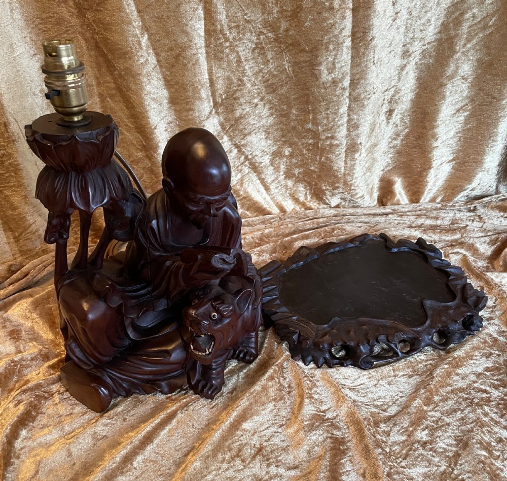 Late nineteenth-century Chinese carved dark wood table lamp depicting a seated scholar figure reading beside a tiger on a carved base with brass bulb holder. View VIII
