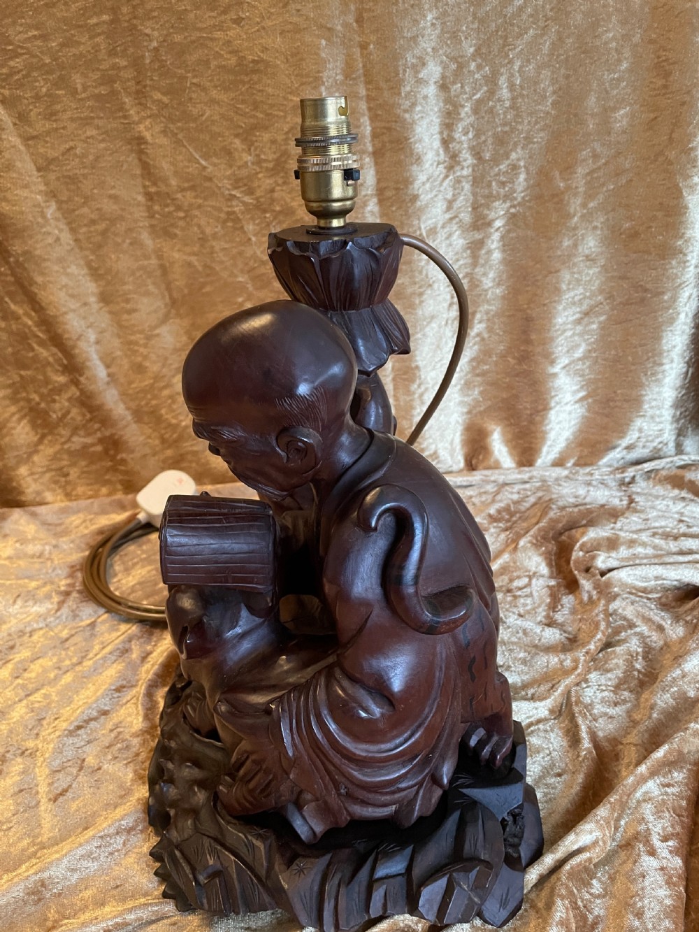 Late nineteenth-century Chinese carved dark wood table lamp depicting a seated scholar figure reading beside a tiger on a carved base with brass bulb holder. View X
