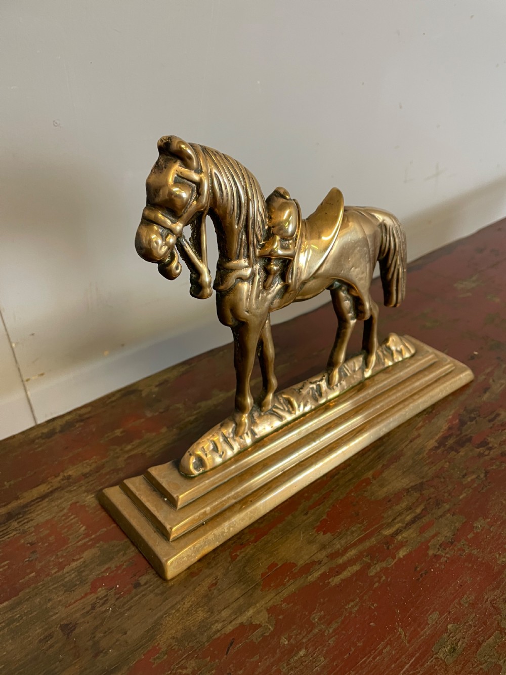 A 19th-century cast brass doorstop featuring a detailed saddled horse standing on a stepped rectangular base. View III