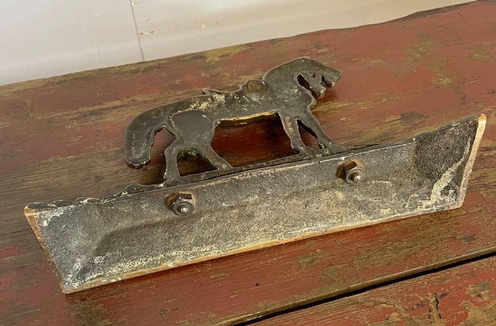 A 19th-century cast brass doorstop featuring a detailed saddled horse standing on a stepped rectangular base. View IV