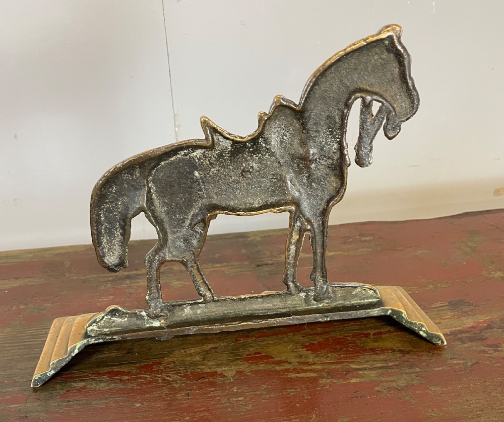 A 19th-century cast brass doorstop featuring a detailed saddled horse standing on a stepped rectangular base. View V