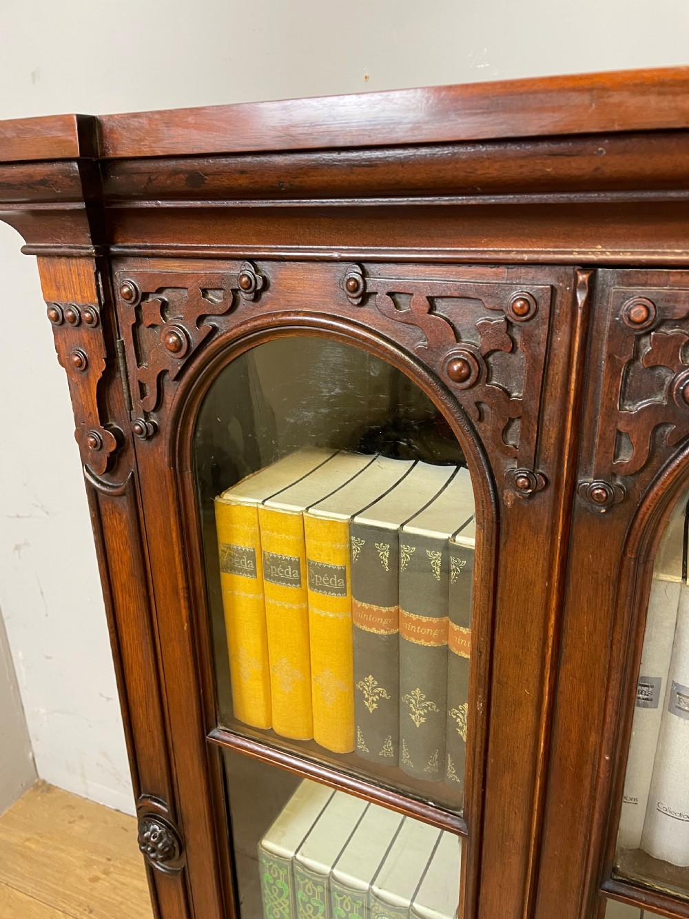 A nineteenth-century walnut low bookcase featuring four arched glazed doors with carved Gothic Revival panel detailing. View III