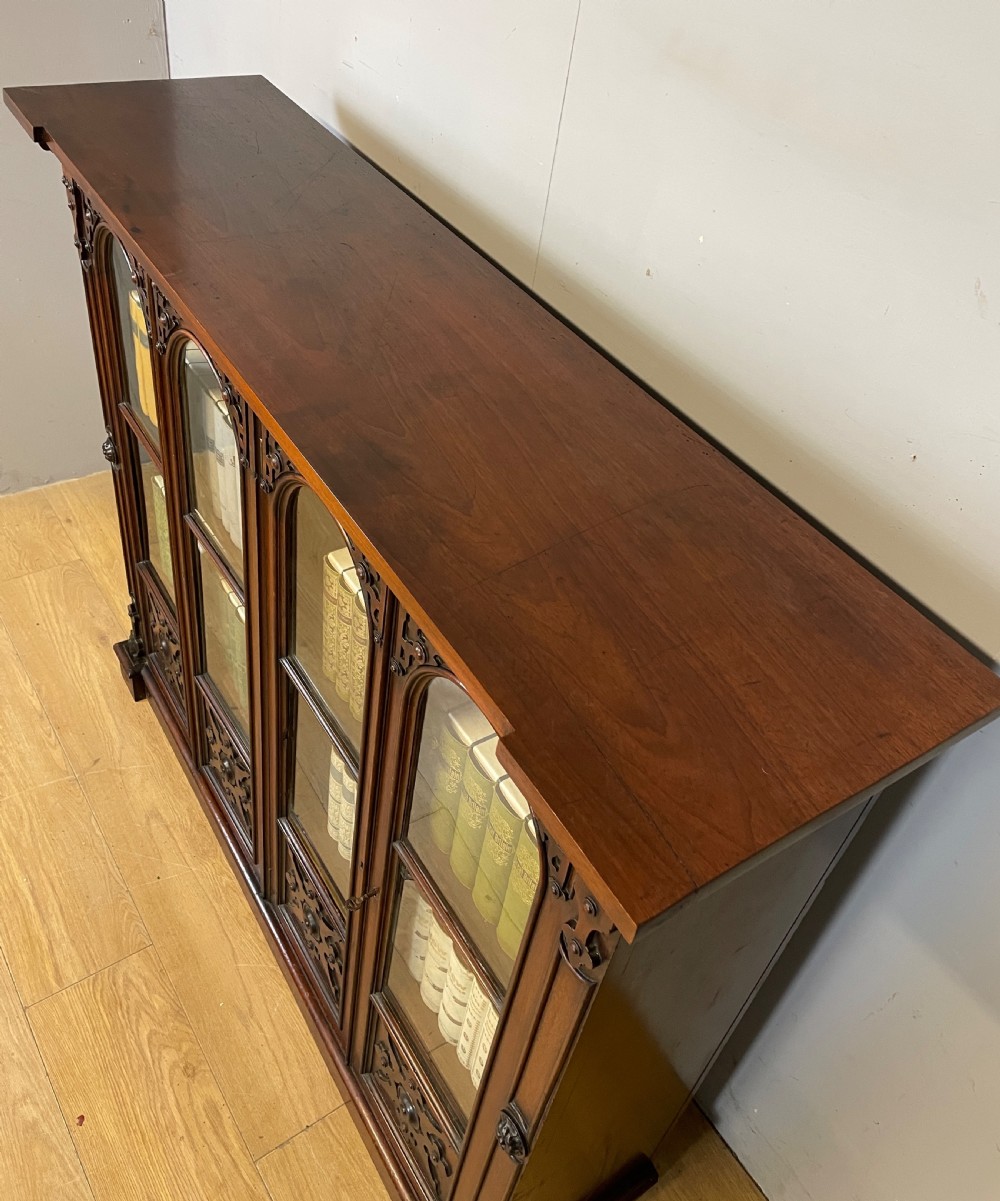 A nineteenth-century walnut low bookcase featuring four arched glazed doors with carved Gothic Revival panel detailing. View VI