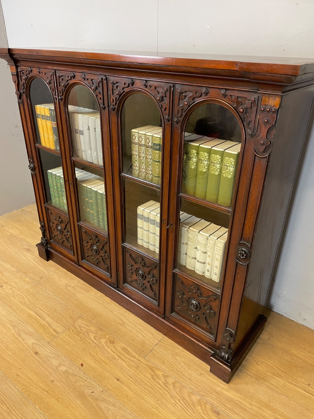 A nineteenth-century walnut low bookcase featuring four arched glazed doors with carved Gothic Revival panel detailing. View VII