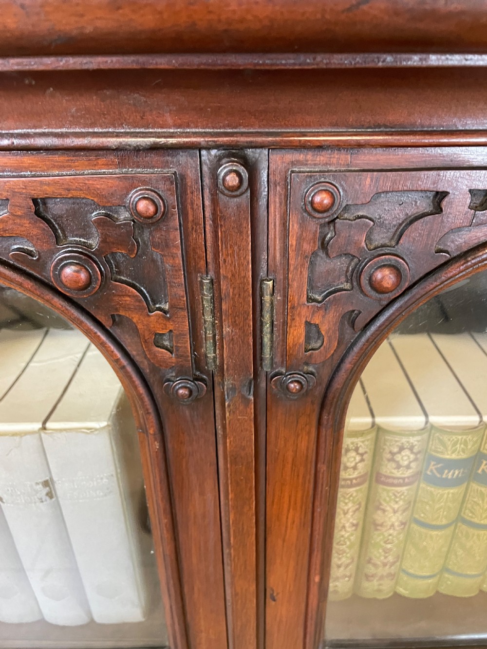 A nineteenth-century walnut low bookcase featuring four arched glazed doors with carved Gothic Revival panel detailing. View X