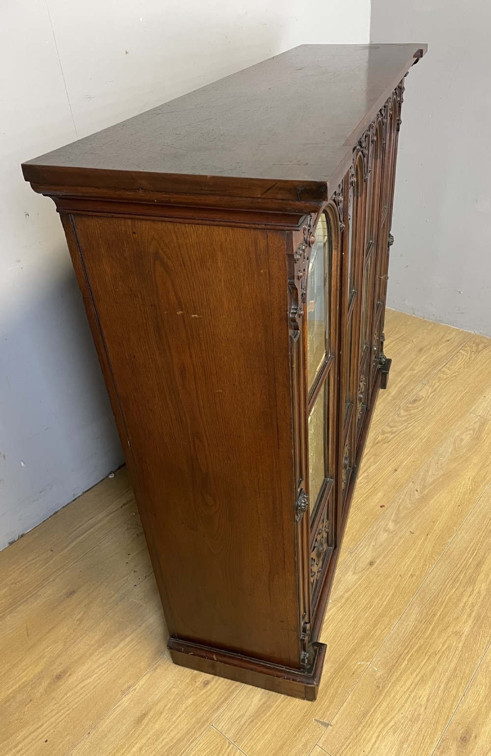 A nineteenth-century walnut low bookcase featuring four arched glazed doors with carved Gothic Revival panel detailing. View XI