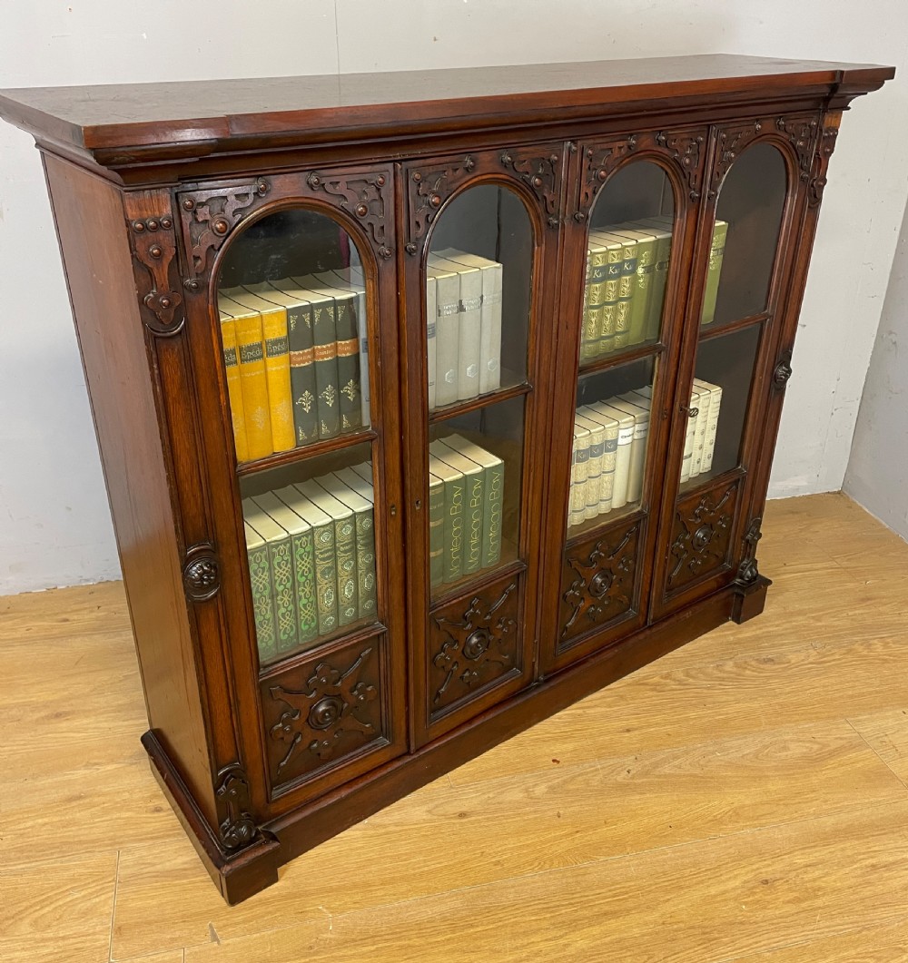 A nineteenth-century walnut low bookcase featuring four arched glazed doors with carved Gothic Revival panel detailing. View XIII