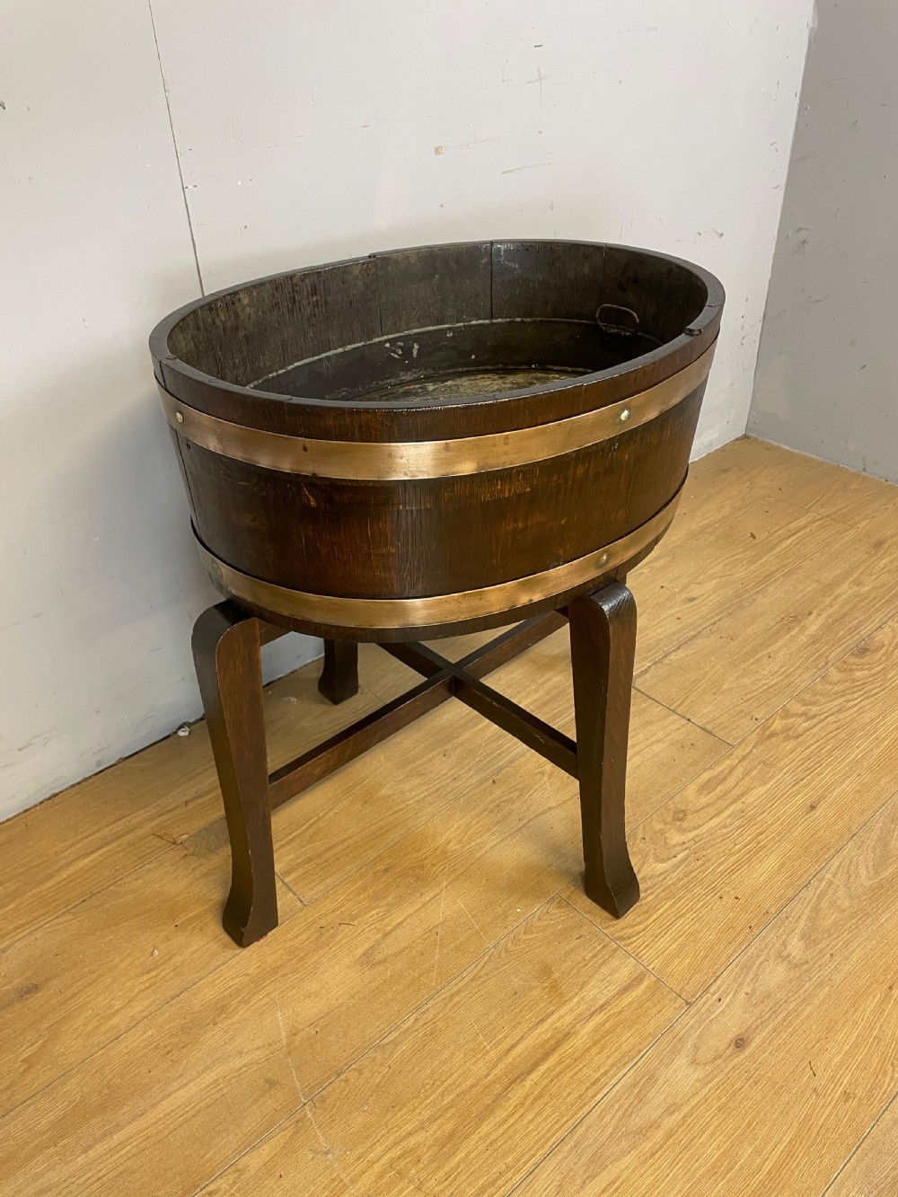 An Edwardian dark oak coopered circular planter with polished brass binding bands, raised on a three-legged wooden stand. View II