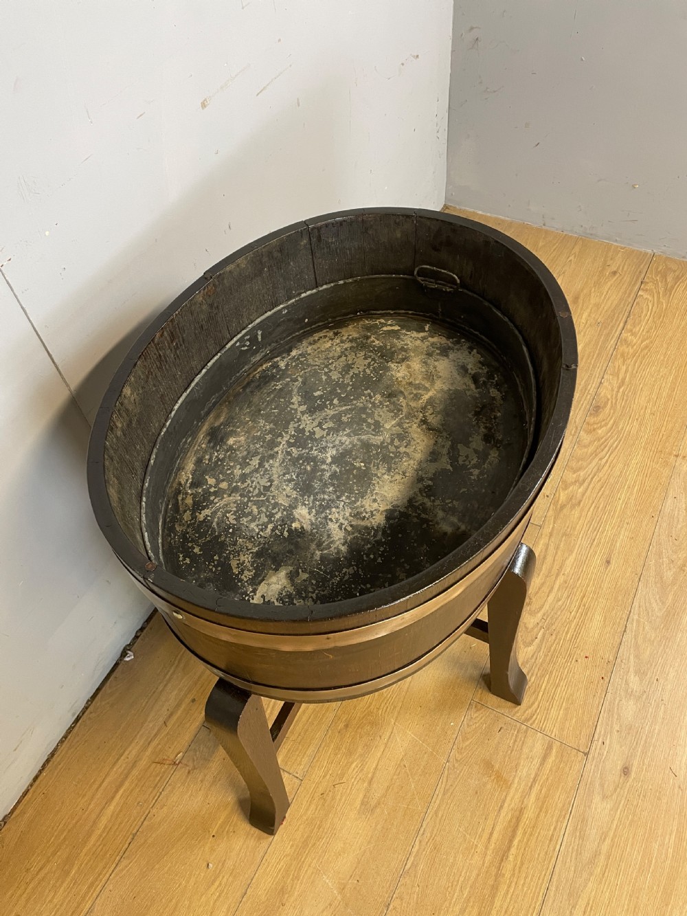 An Edwardian dark oak coopered circular planter with polished brass binding bands, raised on a three-legged wooden stand. View III