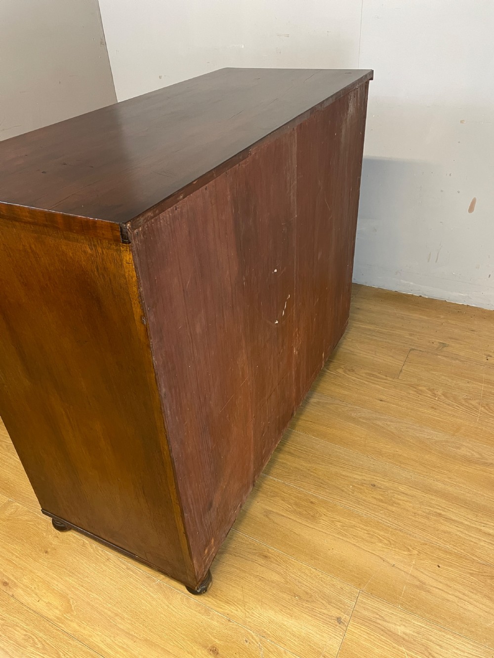 A Late Regency flame mahogany five-height chest of drawers with turned side columns, turned wooden knobs, and brass escutcheons. View IX
