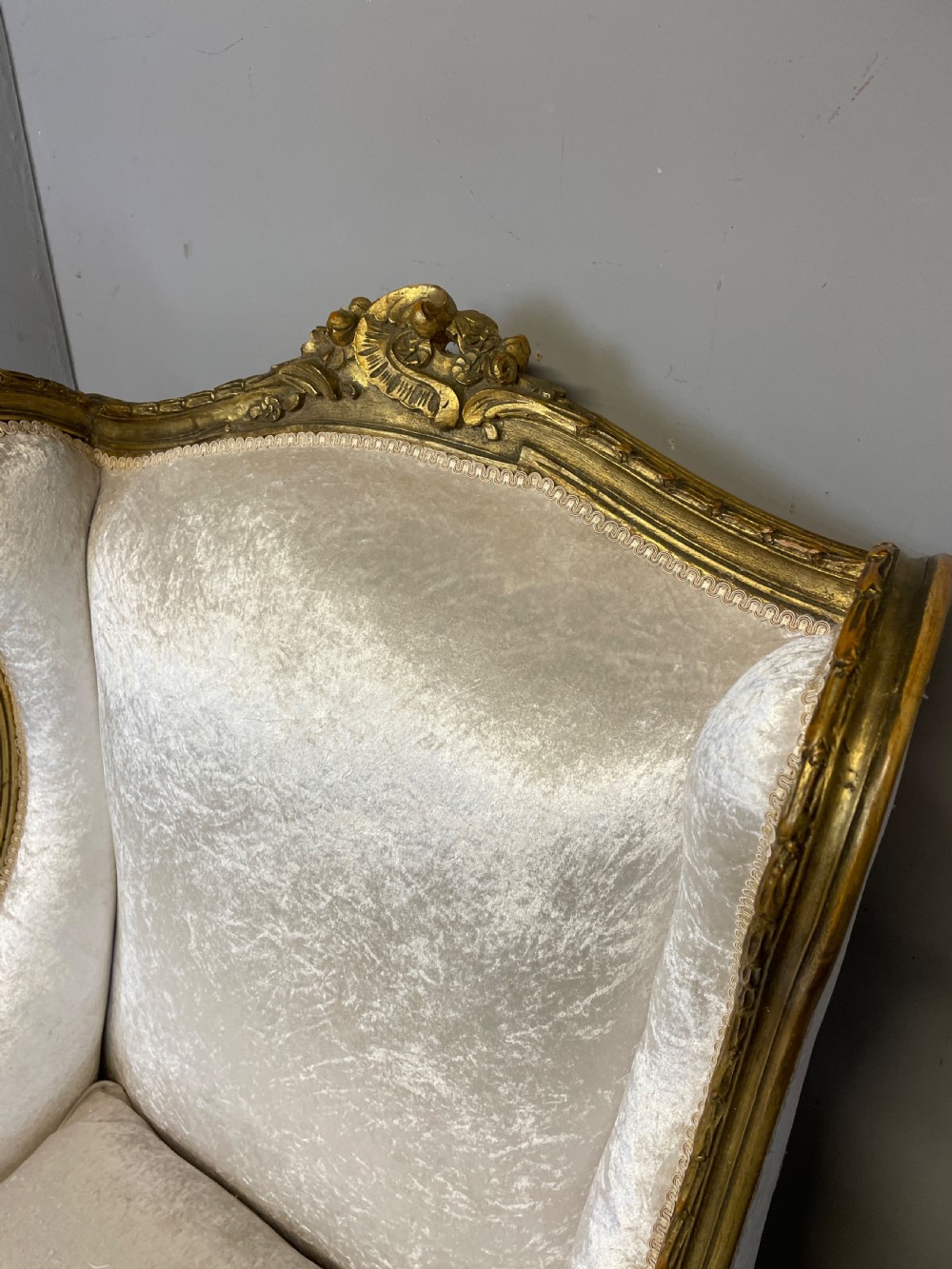 A pair of early twentieth-century French winged armchairs with carved gilded wooden frames and cream velvet upholstery. View II