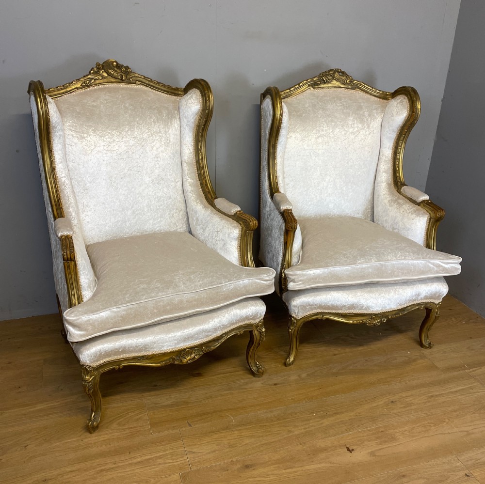 A pair of early twentieth-century French winged armchairs with carved gilded wooden frames and cream velvet upholstery. View III