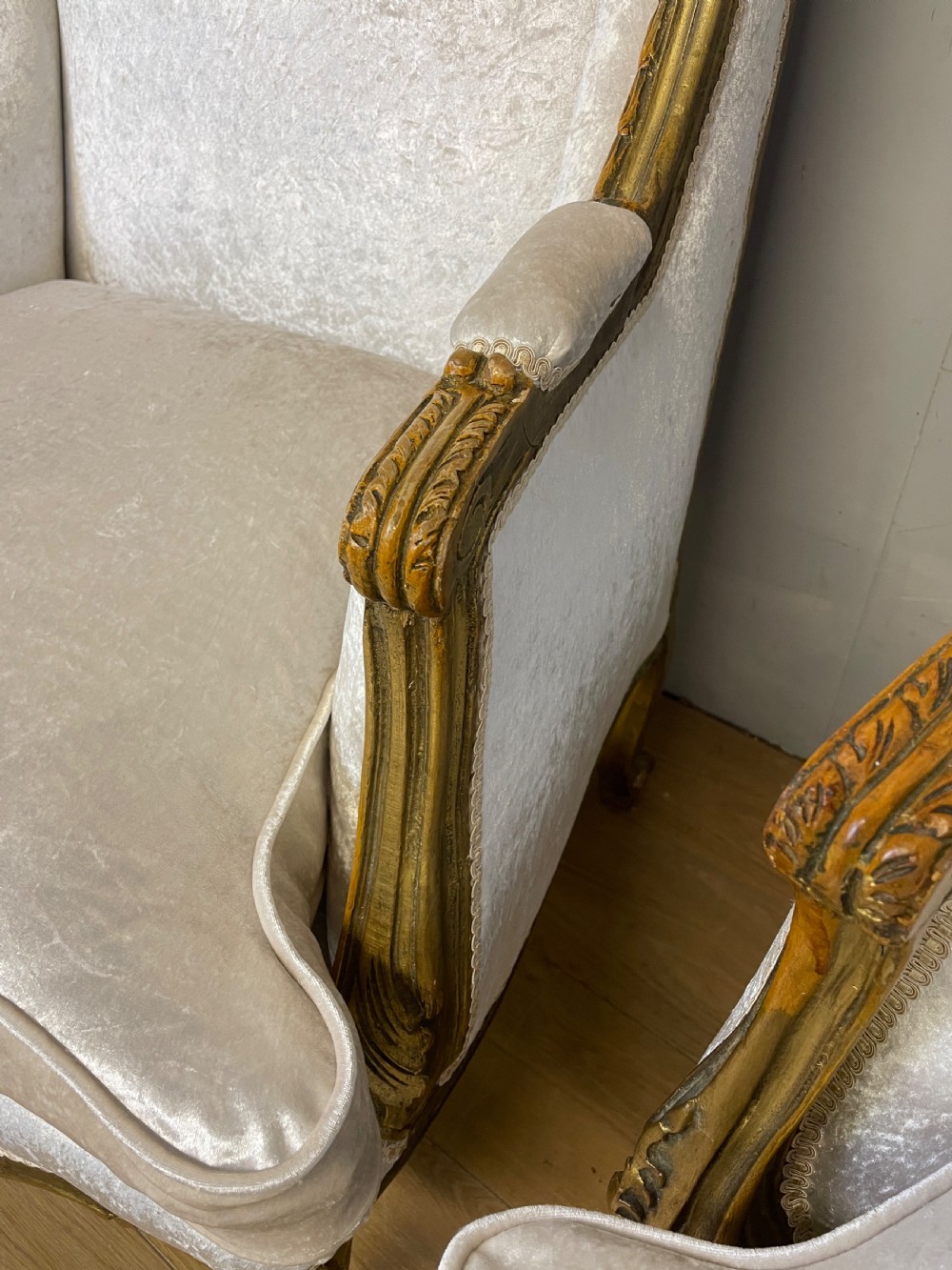 A pair of early twentieth-century French winged armchairs with carved gilded wooden frames and cream velvet upholstery. View V