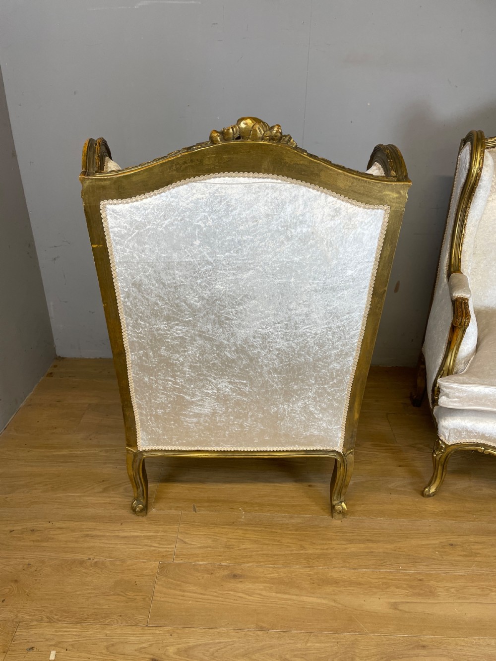 A pair of early twentieth-century French winged armchairs with carved gilded wooden frames and cream velvet upholstery. View VIII
