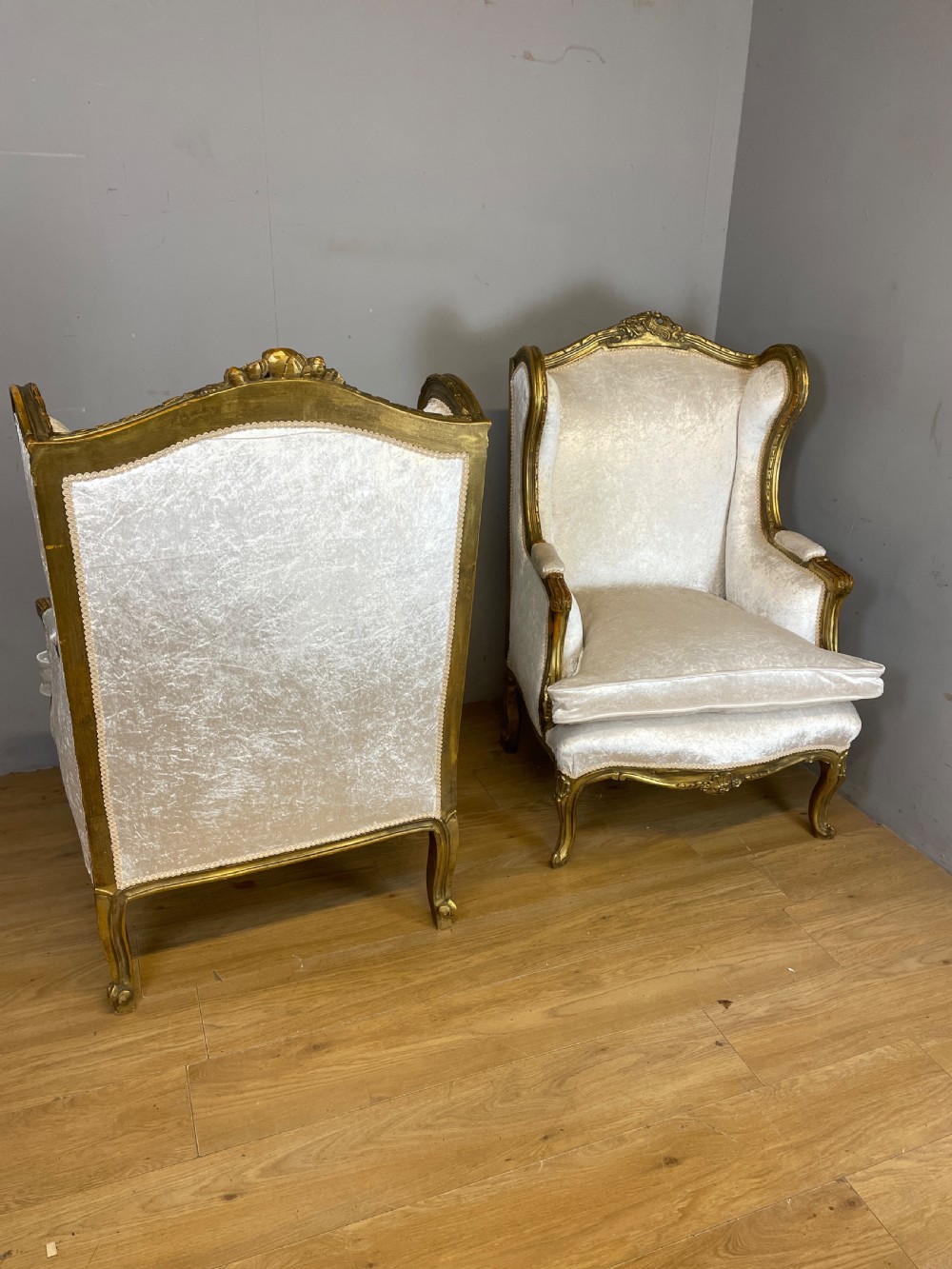 A pair of early twentieth-century French winged armchairs with carved gilded wooden frames and cream velvet upholstery. View IX