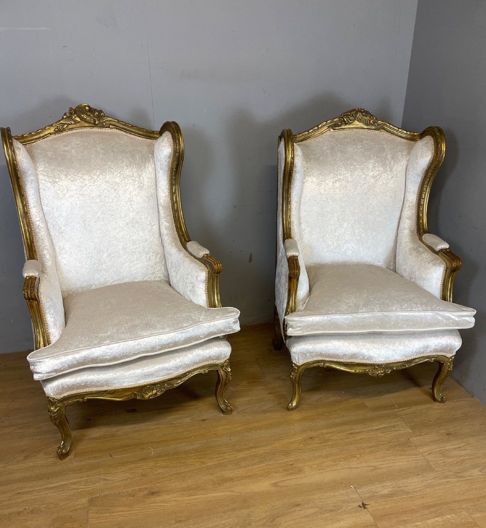 A pair of early twentieth-century French winged armchairs with carved gilded wooden frames and cream velvet upholstery. View XIII