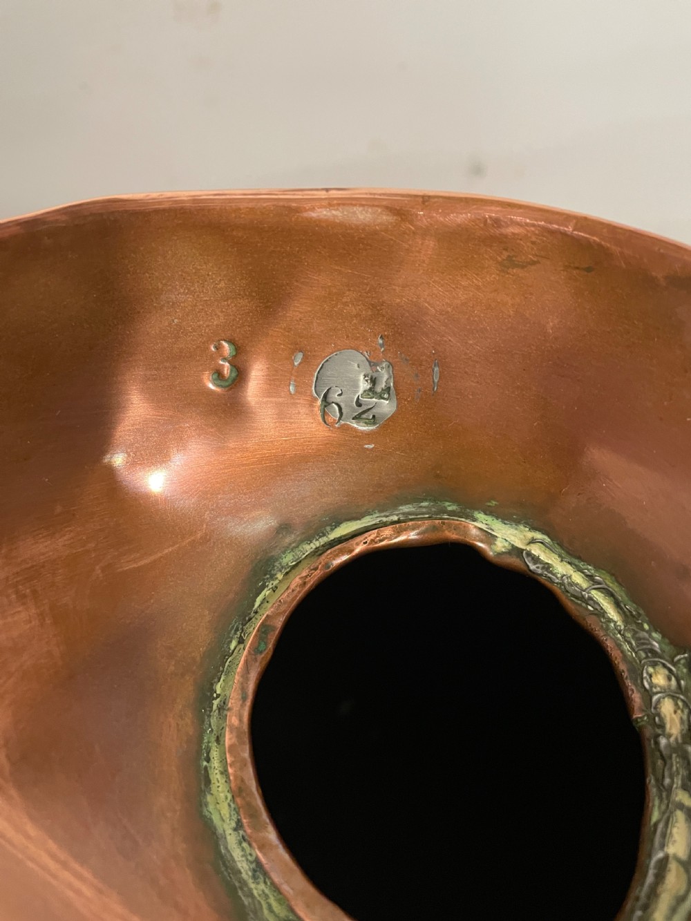 A set of seven graduated Georgian copper measuring jugs featuring haystack bodies and loop handles arranged by size on a wooden surface. View XII