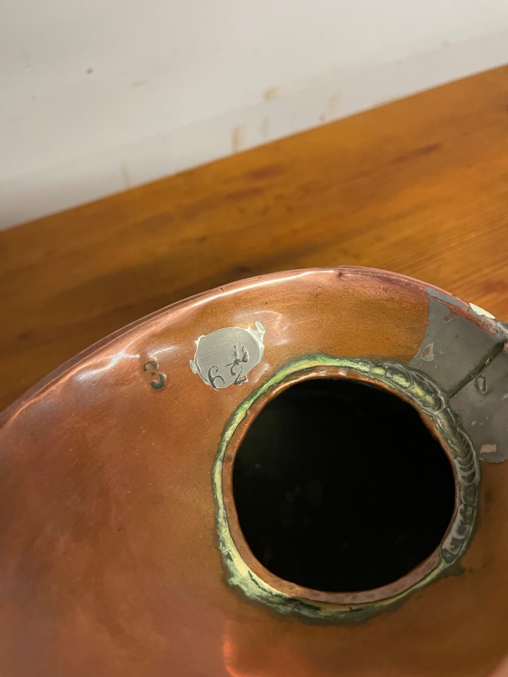 A set of seven graduated Georgian copper measuring jugs featuring haystack bodies and loop handles arranged by size on a wooden surface. View XIII