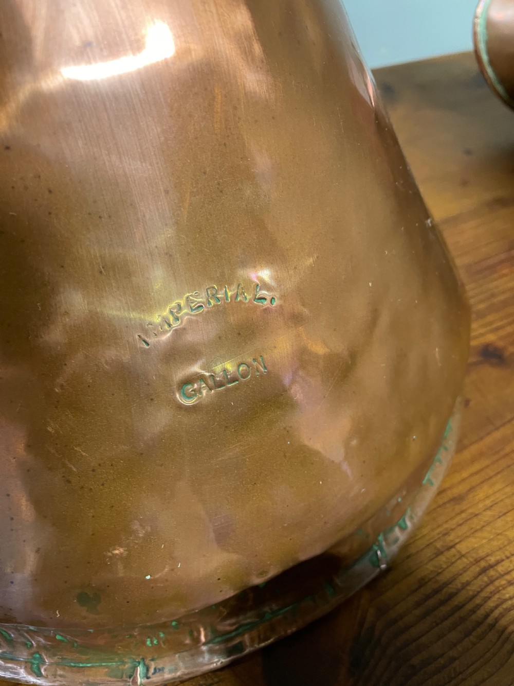 A set of seven graduated Georgian copper measuring jugs featuring haystack bodies and loop handles arranged by size on a wooden surface. View XIX