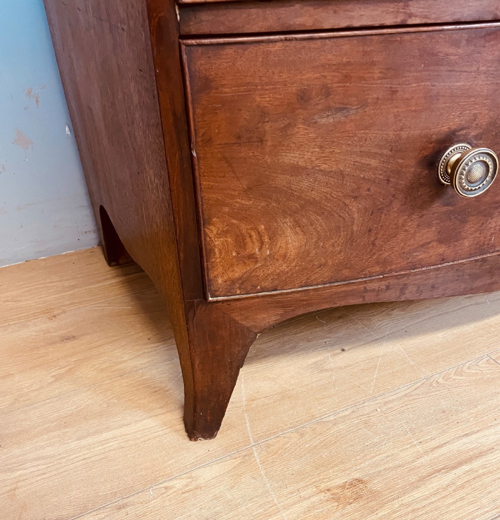 An antique Regency mahogany bow-front chest of drawers featuring three long drawers with brass knobs, brass keyhole escutcheons, and curved bracket feet. View VIII