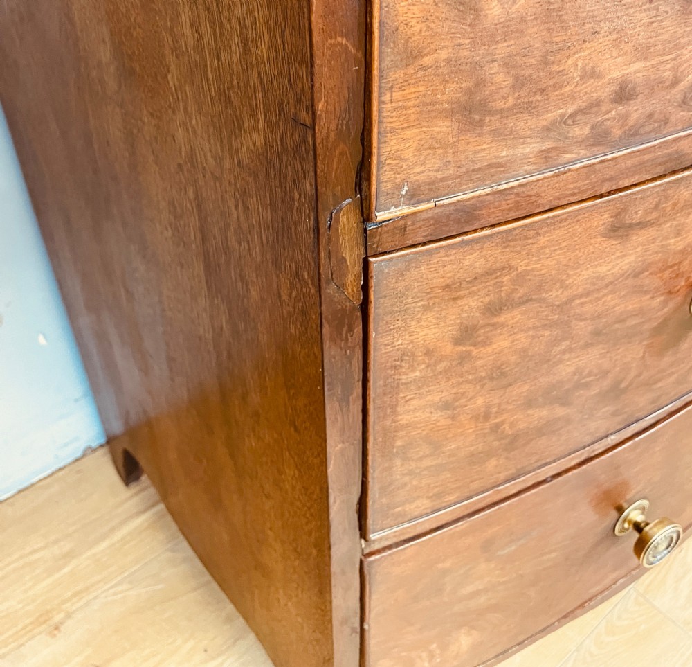 An antique Regency mahogany bow-front chest of drawers featuring three long drawers with brass knobs, brass keyhole escutcheons, and curved bracket feet. View XIV