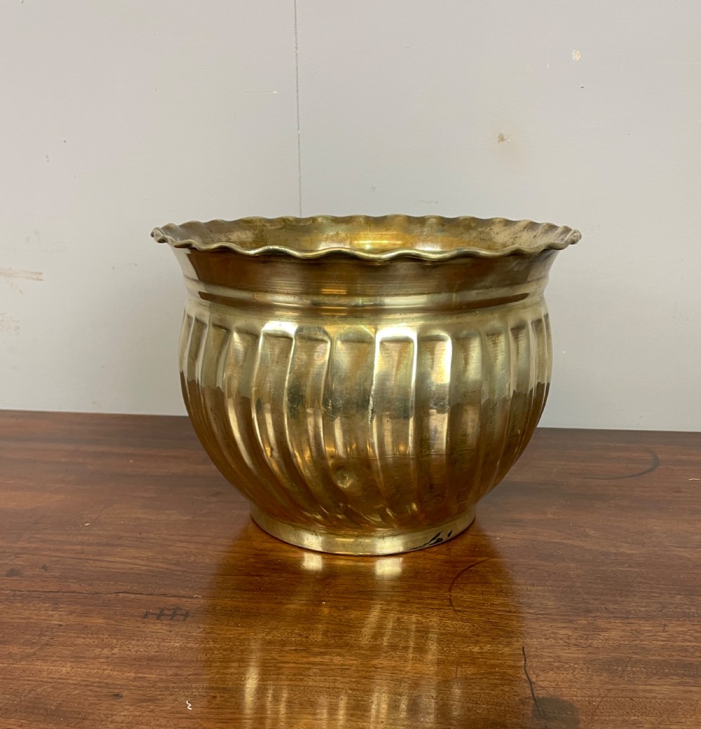 A round brass jardiniere with spiral fluted sides, a scalloped upper rim, and a flat circular base. View III