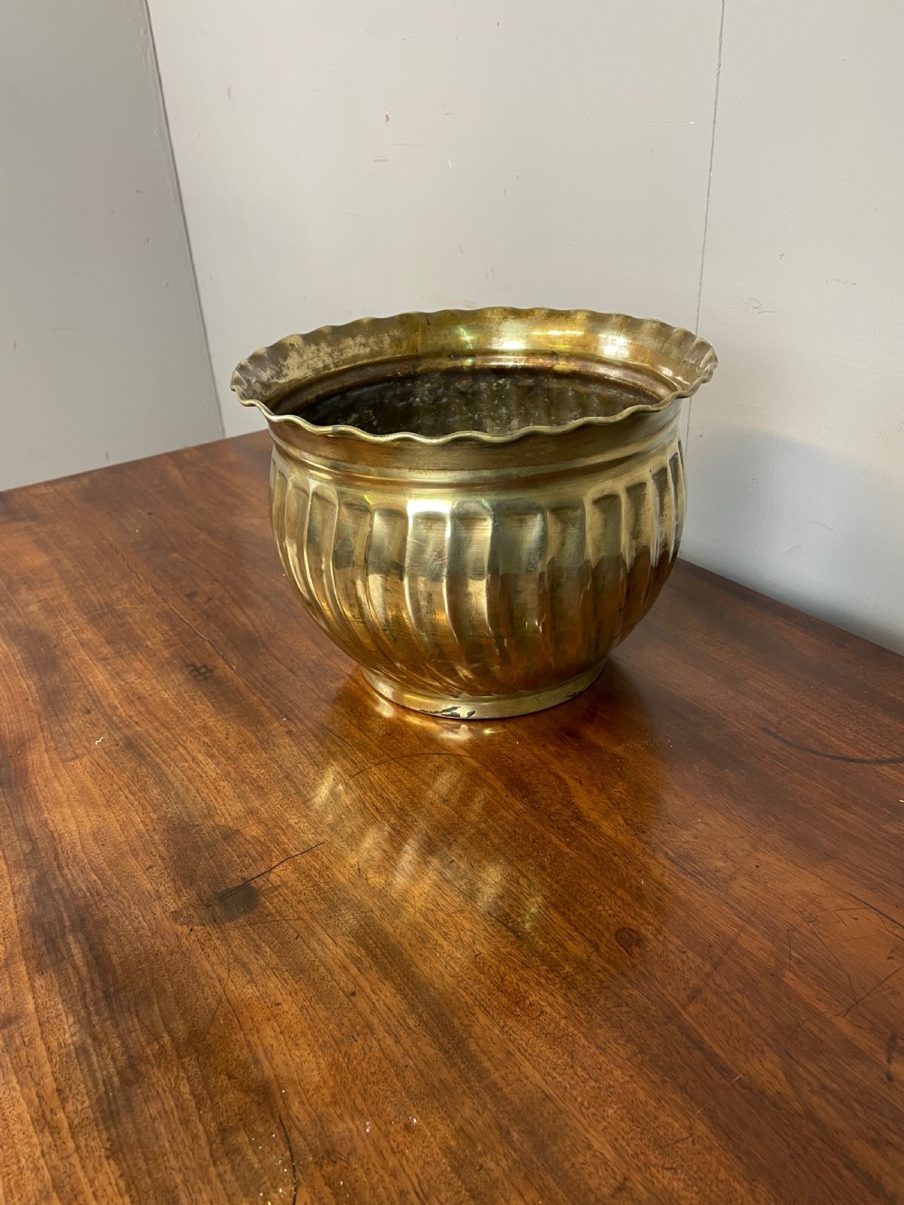 A round brass jardiniere with spiral fluted sides, a scalloped upper rim, and a flat circular base. View IV