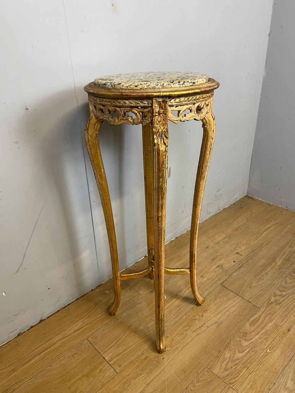 An Edwardian carved giltwood torchere featuring a circular grey marble top, slender cabriole legs, pierced aprons, and an X-frame stretcher. View V