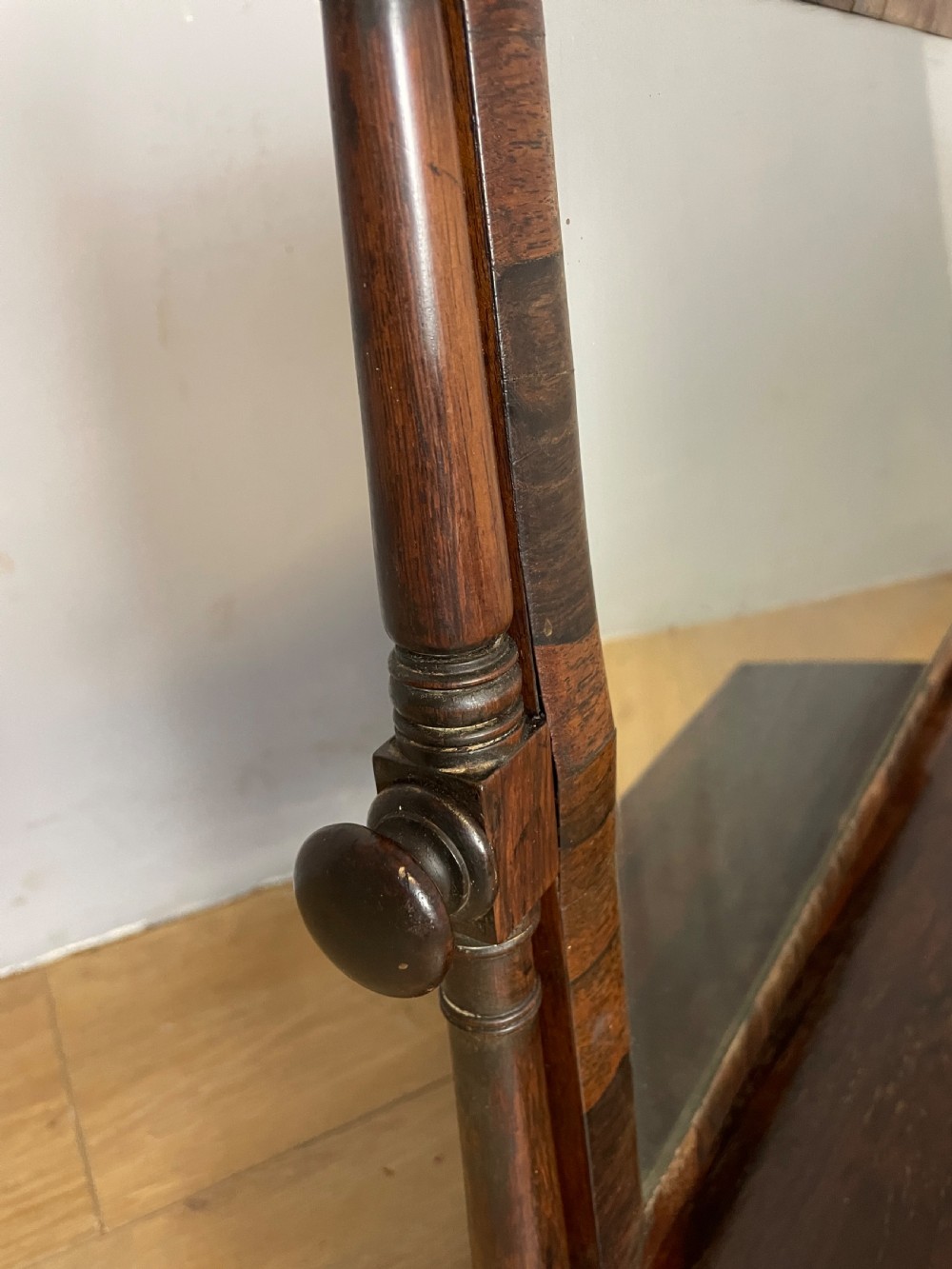 An early Victorian dark rosewood dressing table mirror featuring turned support columns, finials, and a rectangular swivelling frame resting on a plinth drawer base. View V