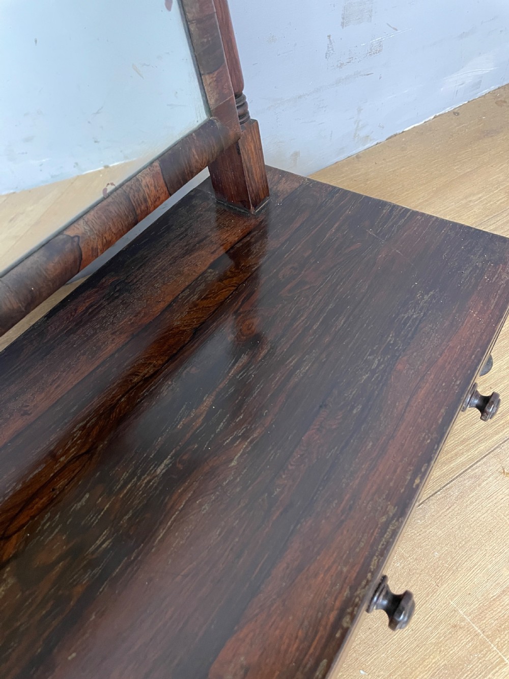 An early Victorian dark rosewood dressing table mirror featuring turned support columns, finials, and a rectangular swivelling frame resting on a plinth drawer base. View VII