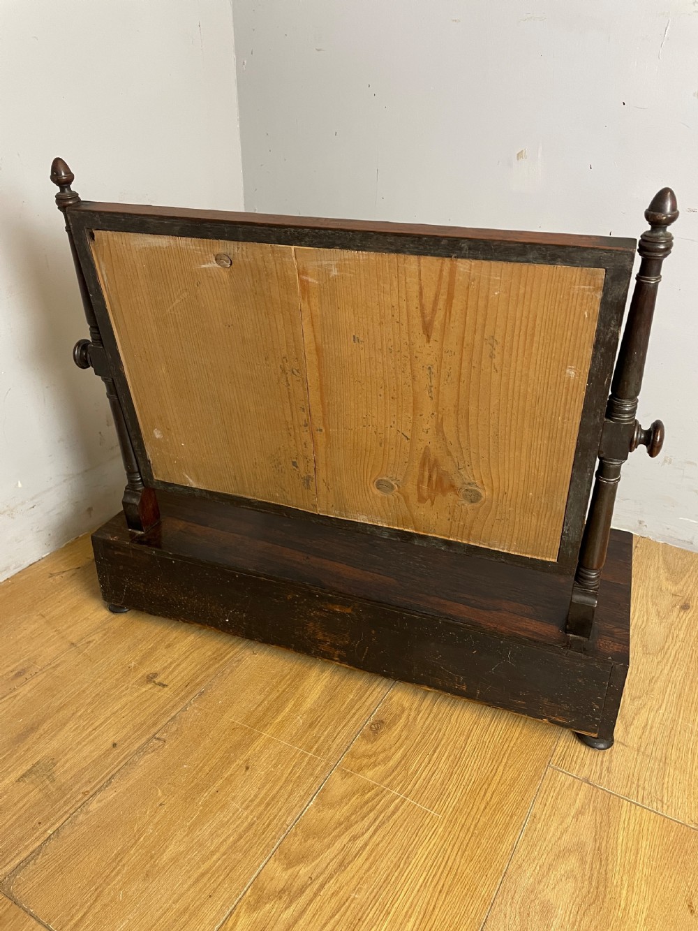 An early Victorian dark rosewood dressing table mirror featuring turned support columns, finials, and a rectangular swivelling frame resting on a plinth drawer base. View IX