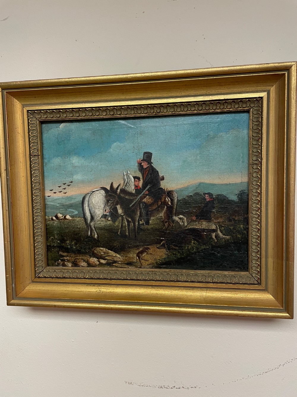 A 19th-century oil painting on canvas depicting riders and dogs in a rural landscape set within a moulded gilt frame. View II