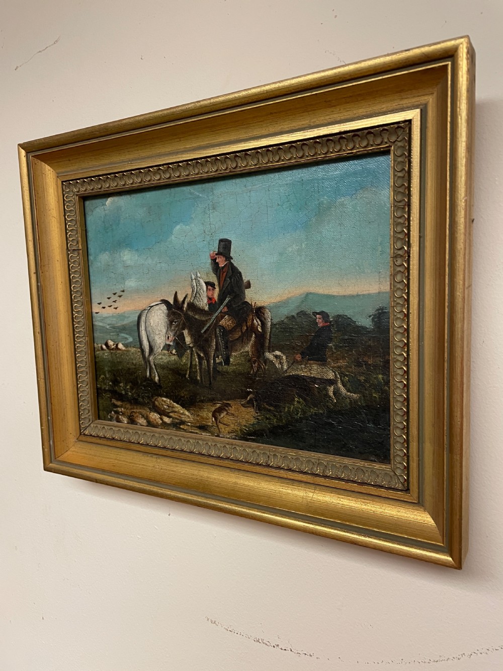 A 19th-century oil painting on canvas depicting riders and dogs in a rural landscape set within a moulded gilt frame. View V