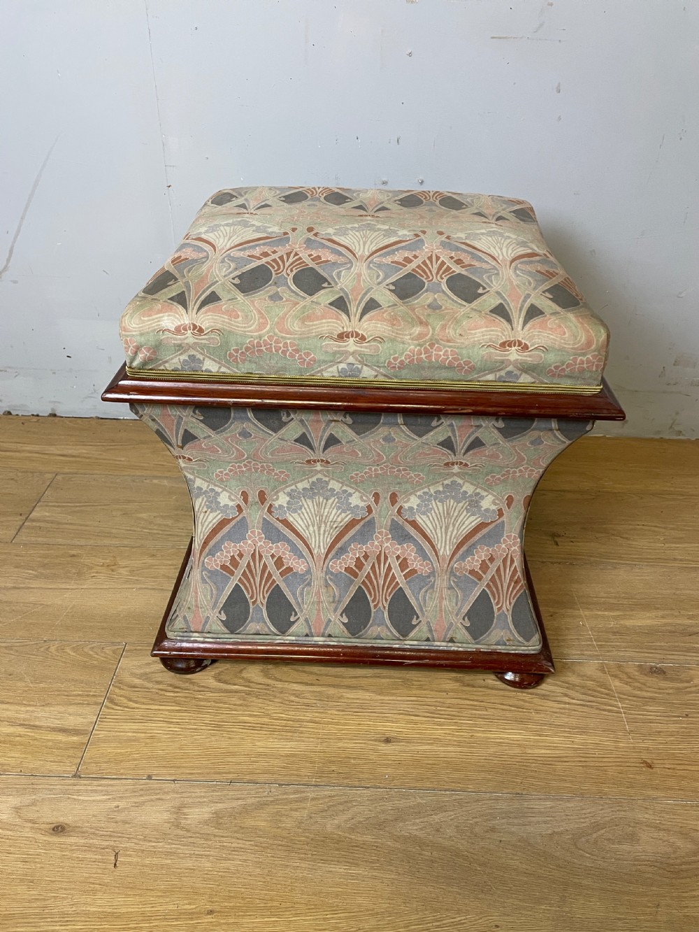 A nineteenth-century square waisted ottoman stool upholstered in a floral Liberty fabric with dark mahogany trim and bun feet. View II
