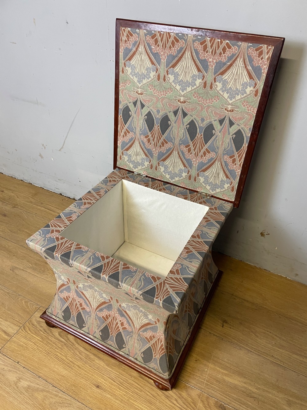 A nineteenth-century square waisted ottoman stool upholstered in a floral Liberty fabric with dark mahogany trim and bun feet. View V