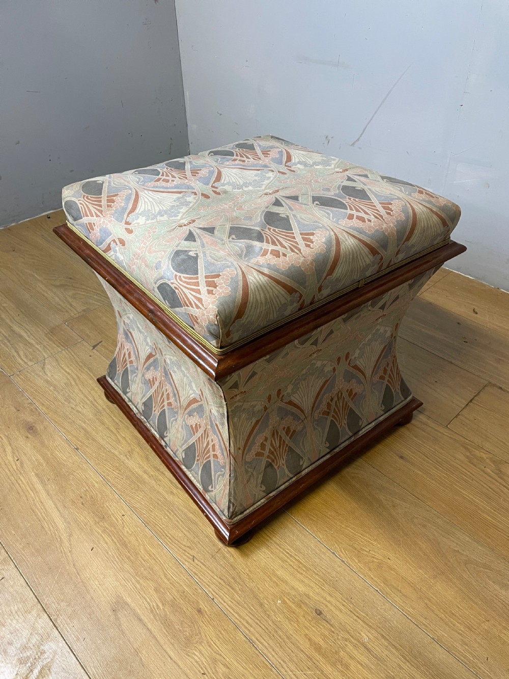A nineteenth-century square waisted ottoman stool upholstered in a floral Liberty fabric with dark mahogany trim and bun feet. View VII