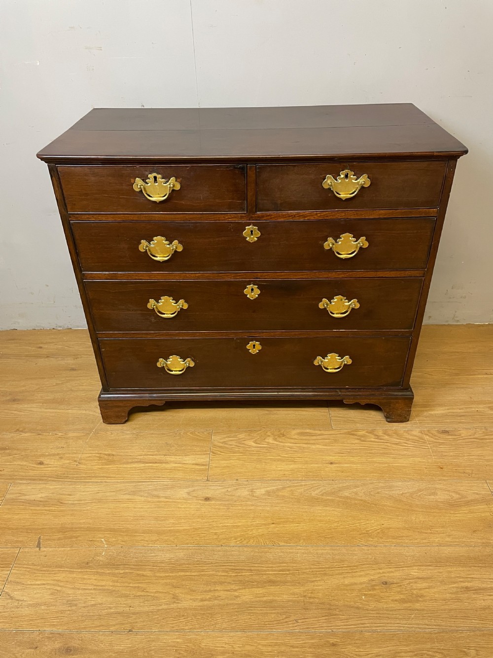 A late 18th-century Georgian solid mahogany four-height chest of drawers with two short over three long drawers, brass handles, and bracket feet. View II
