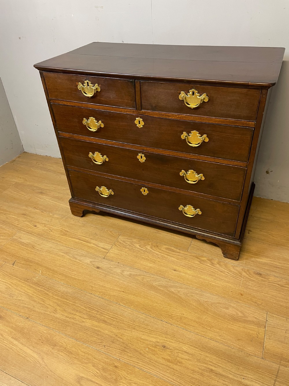 A late 18th-century Georgian solid mahogany four-height chest of drawers with two short over three long drawers, brass handles, and bracket feet. View III
