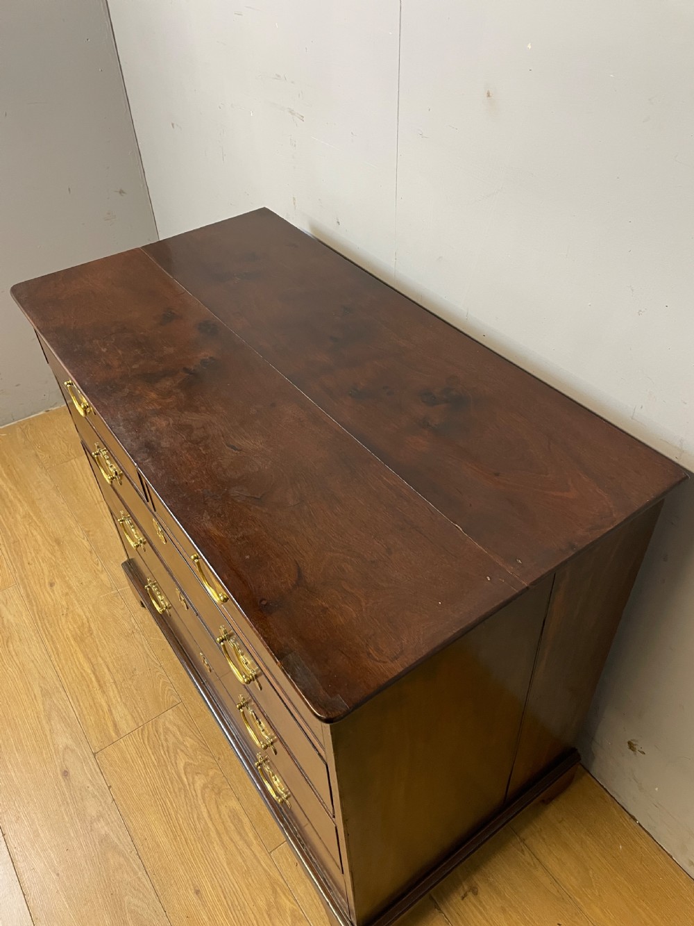 A late 18th-century Georgian solid mahogany four-height chest of drawers with two short over three long drawers, brass handles, and bracket feet. View V