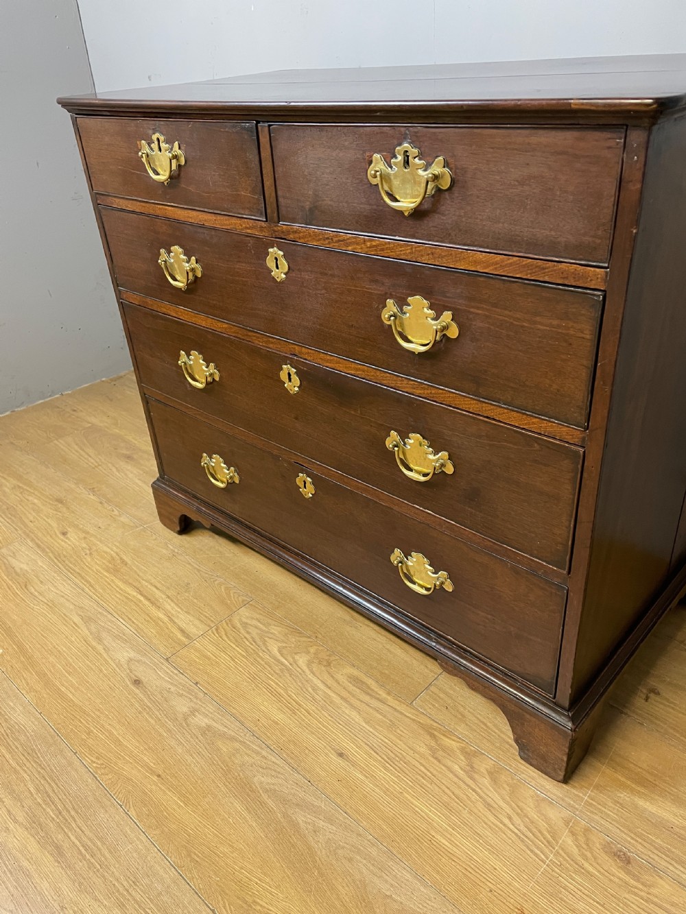 A late 18th-century Georgian solid mahogany four-height chest of drawers with two short over three long drawers, brass handles, and bracket feet. View VI