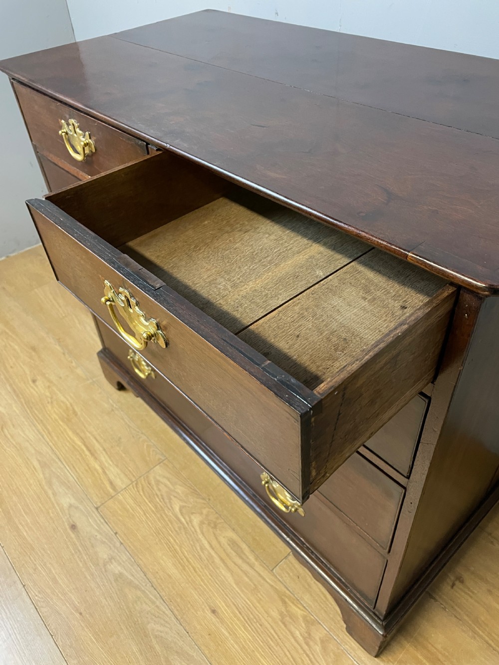 A late 18th-century Georgian solid mahogany four-height chest of drawers with two short over three long drawers, brass handles, and bracket feet. View VII